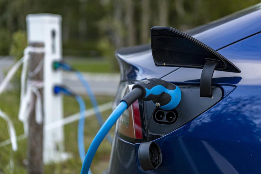 Close-up of a blue electric vehicle being plugged in to charge