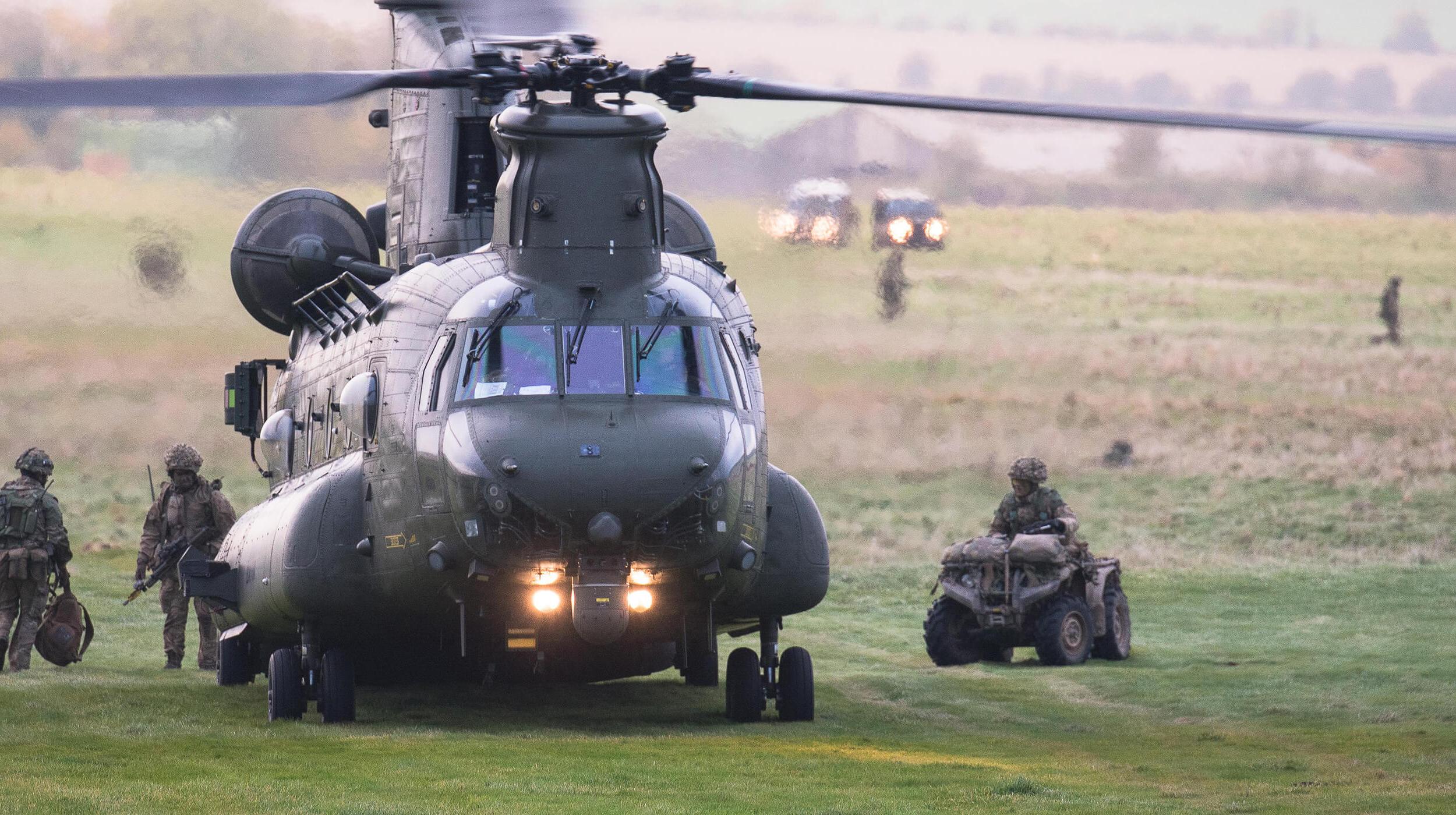 Royal Air Force Chinook helicopter on a field, with members of armed forces nearby